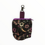 Papillon de Lune Leckerlibeutel für Hunde von Doggies Couture mit elegantem Schmetterlings-, Blumen- und Mond-Design in Rosa, Lila, Gold und Petrol auf schwarzem Hintergrund, mit Zippverschluss und praktischem Karabiner.